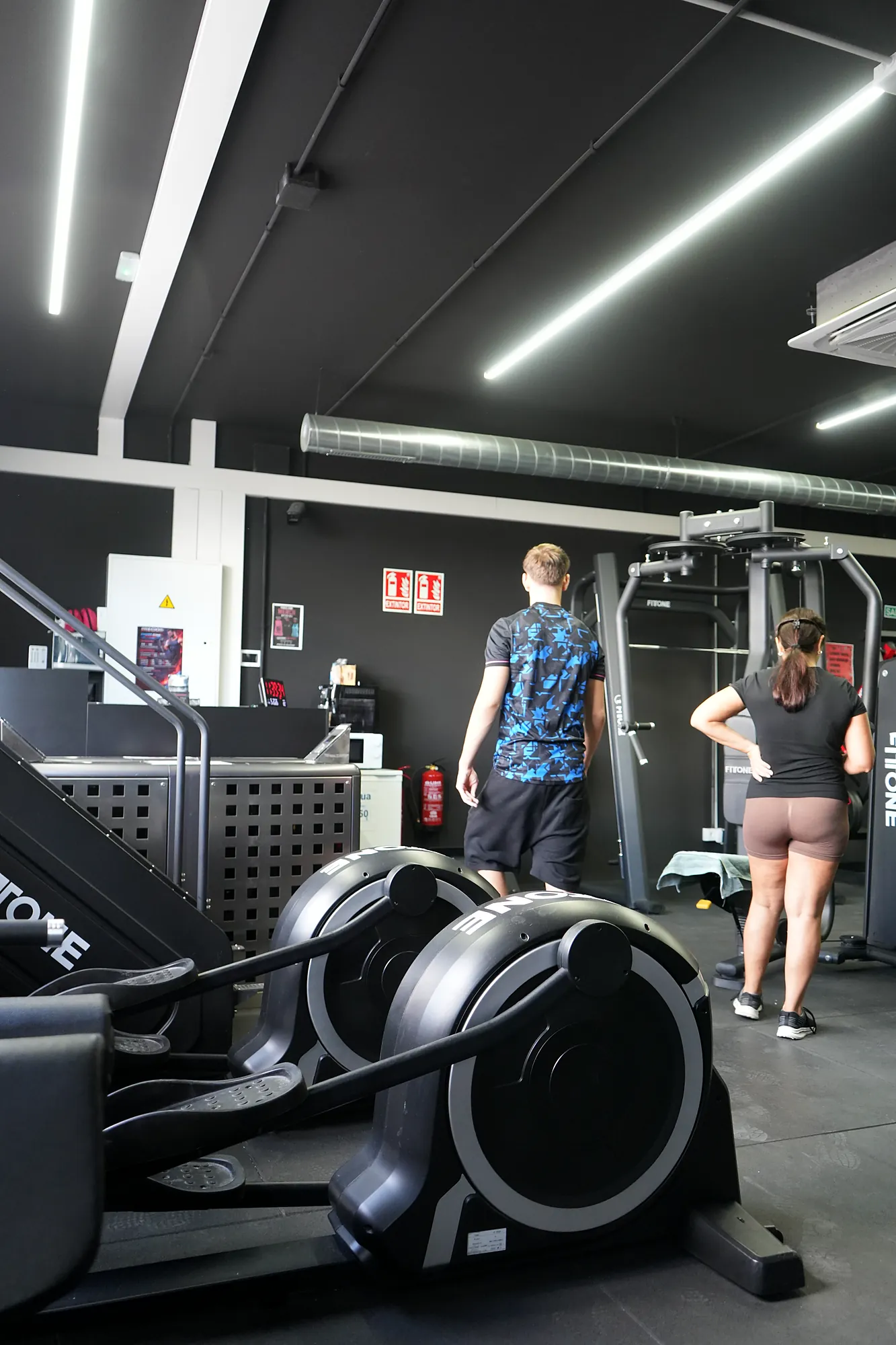 Elíptica en primer plano y socios en la zona de cardio
